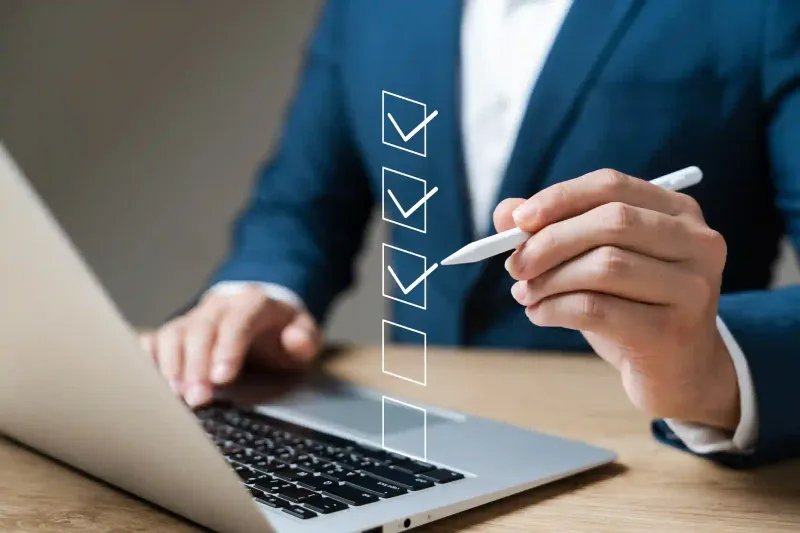 Profesional con stylus marca checklist de tareas de cumplimiento tributario junto a laptop