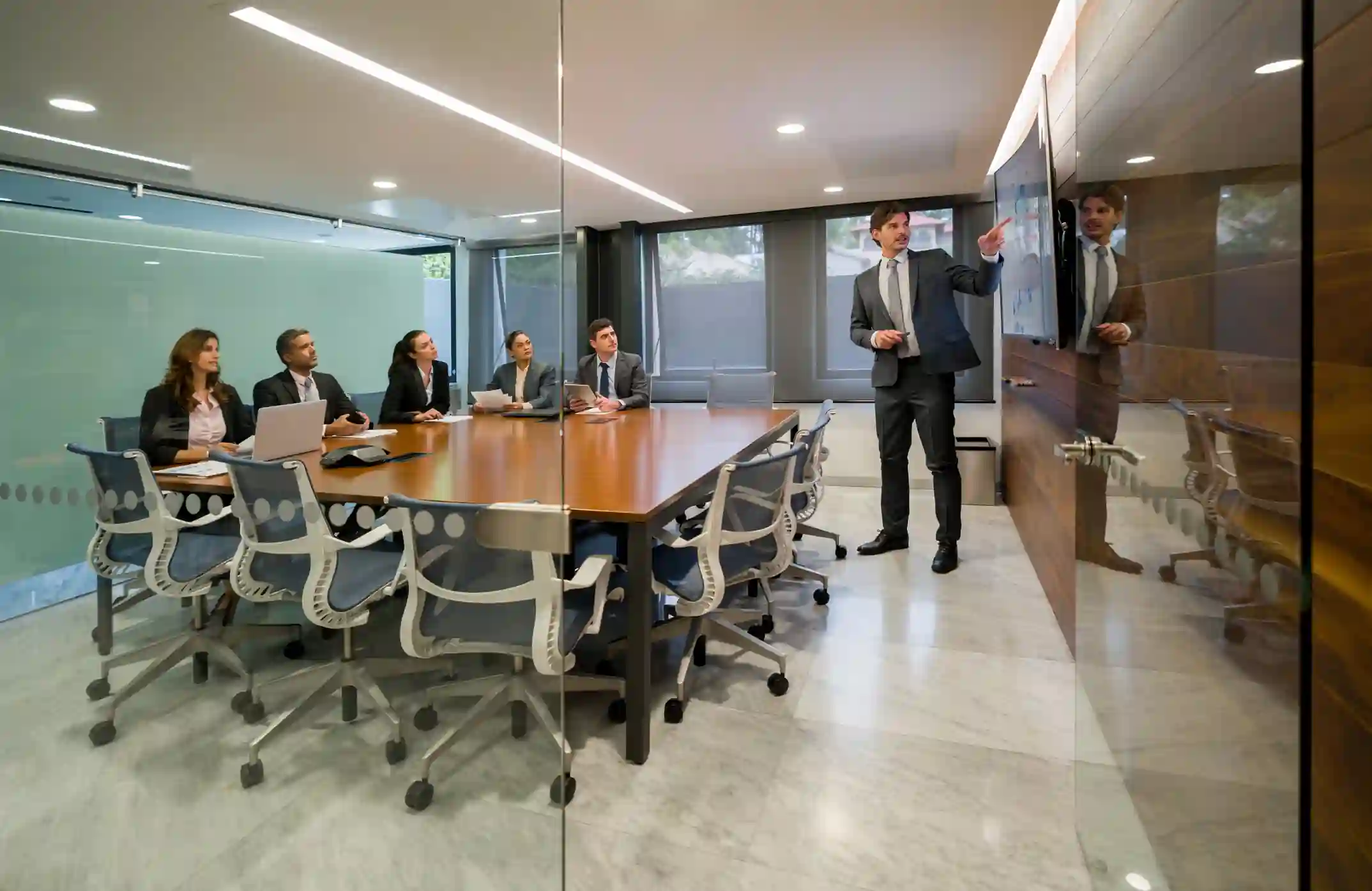 Hombre presentando estrategia a equipo en sala de reuniones corporativa moderna